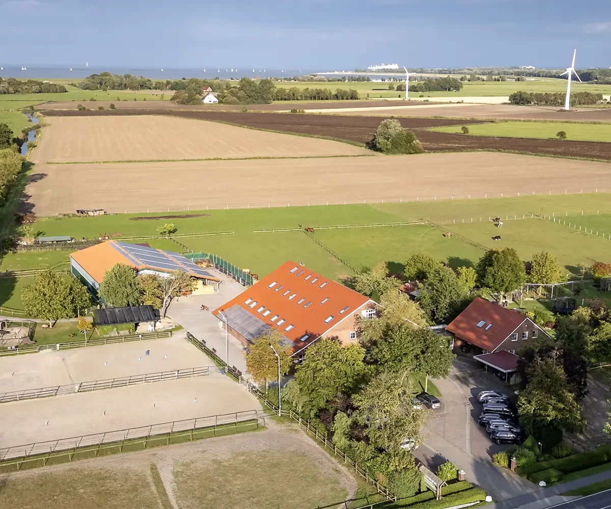 Blick auf den Traberhof zwischen Bäumen und Weiden